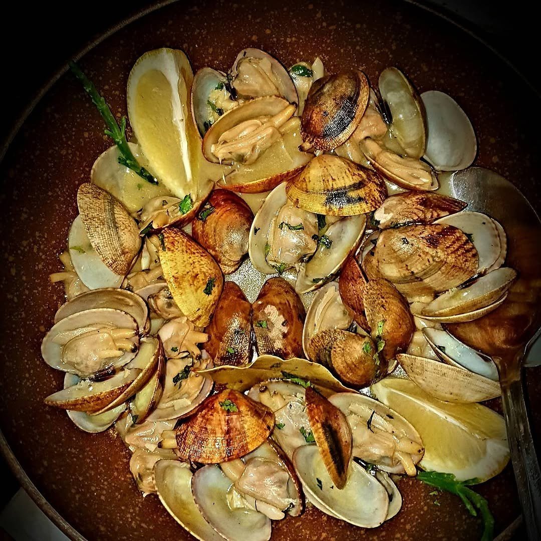Tacho de amêijoas abertas com rodelas de limão e coentros